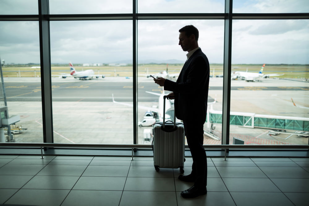 businessman with luggage using mobile phone