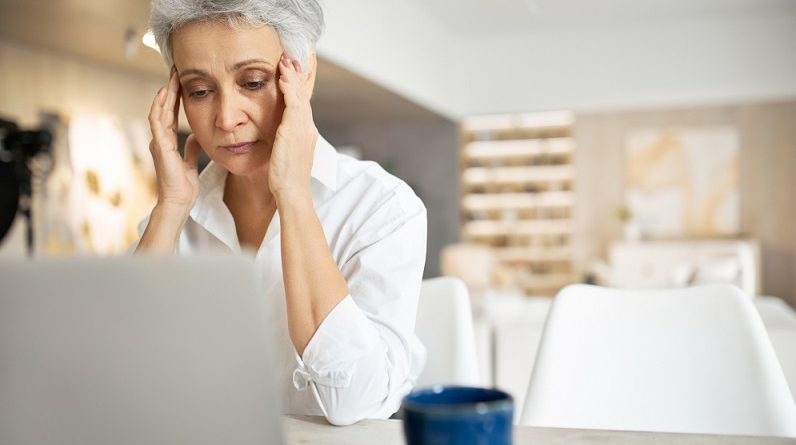 senior sad woman with gray hair working laptop rubbing eyes hiding tears full restless thoughts